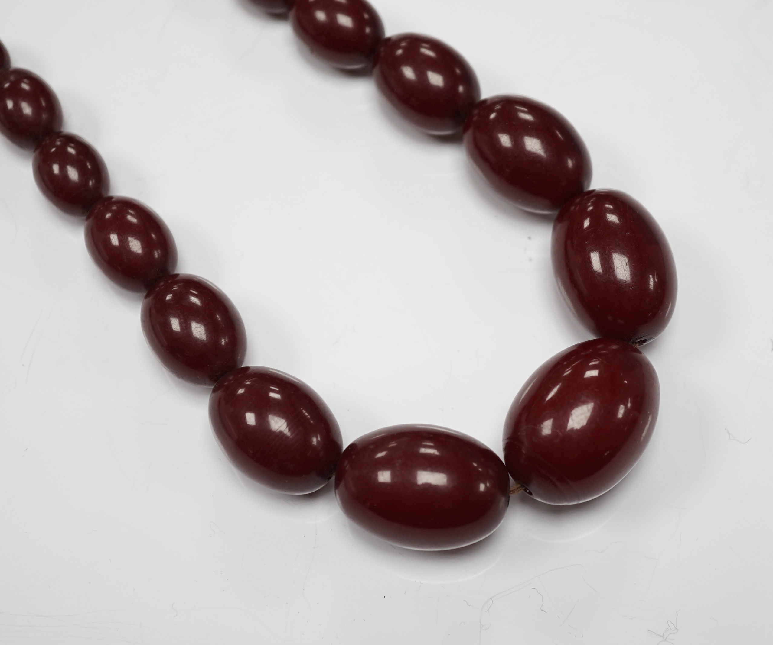 A single strand graduated simulated oval cherry amber bead necklace, 58cm, gross weight 80 grams.